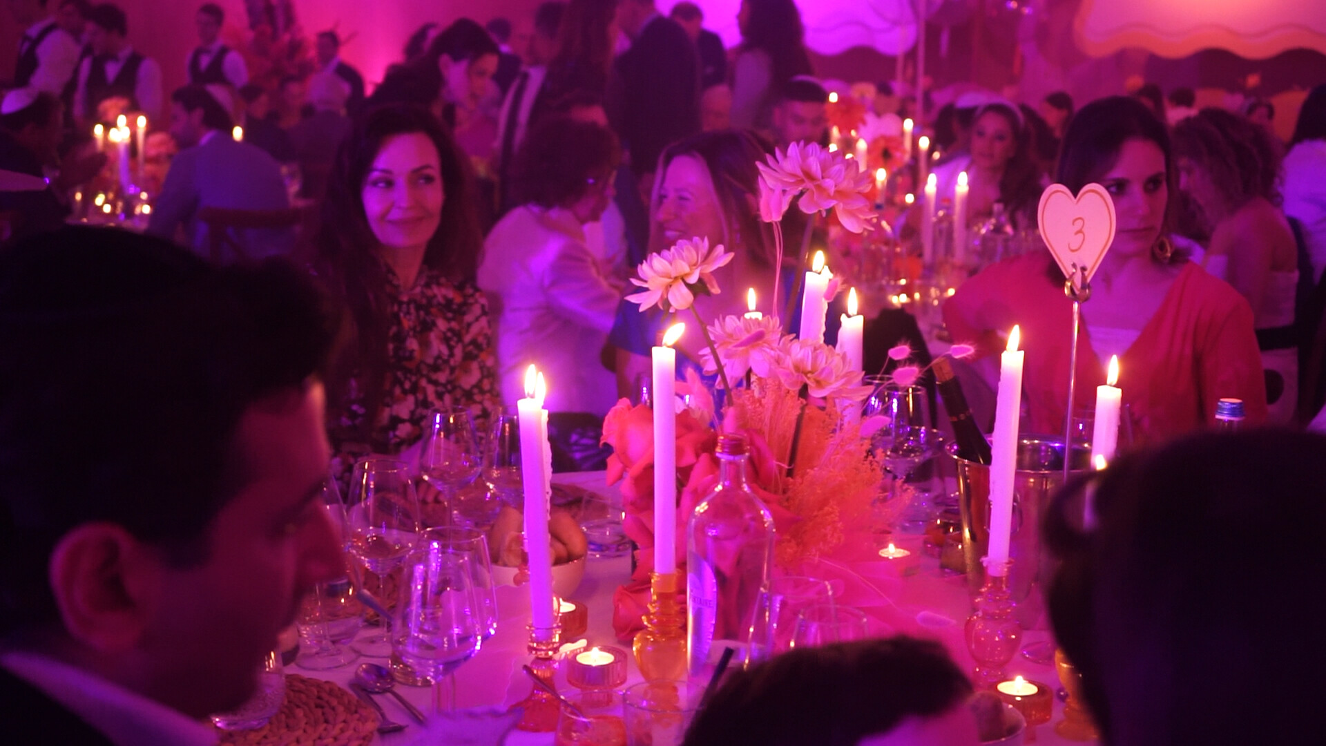 Guests conversing around a flower- and candle-filled gala table.