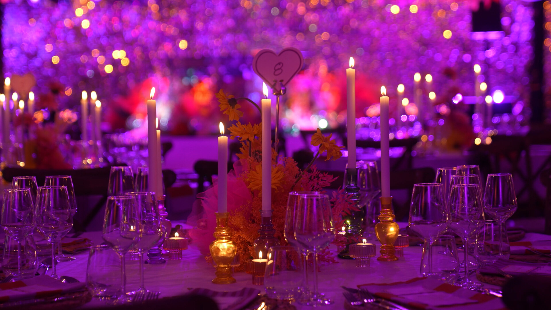 Candlelit gala table against a glittering violet backdrop.